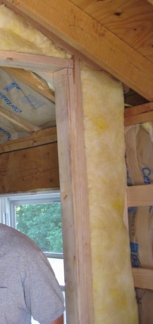 Yellow fiberglass lining a doorway, walls and ceiling inside of a room with a man in a gray shirt standing next to it.