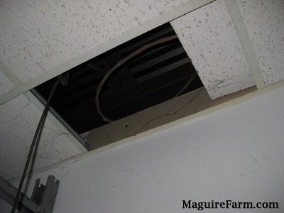 A ceiling panel pushed to the side showing a black space above the ceiling