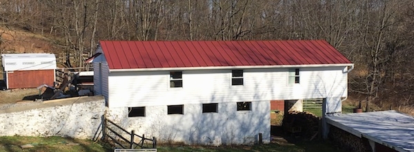 A white barn with a red tin roof.