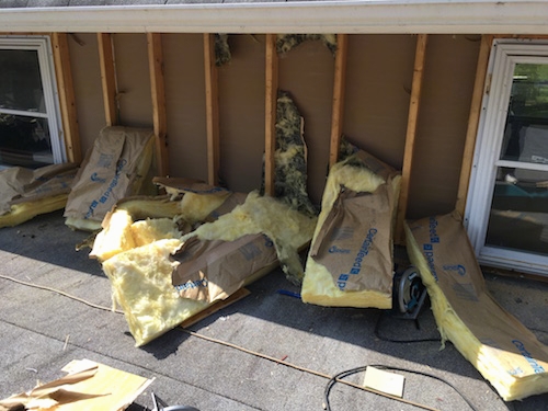 Yellow fiberglass batts falling out of a wall of a barn.