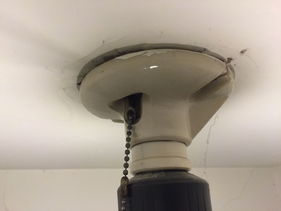 the bottom of a ceiling light fixture with a crack between the ceiling and the base of the light