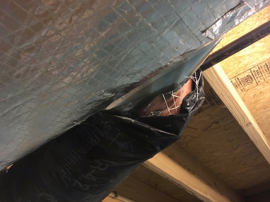 black flex duct work in a basement ceiling with the fiberglass ends exposed to the air next to a larger silver air duct