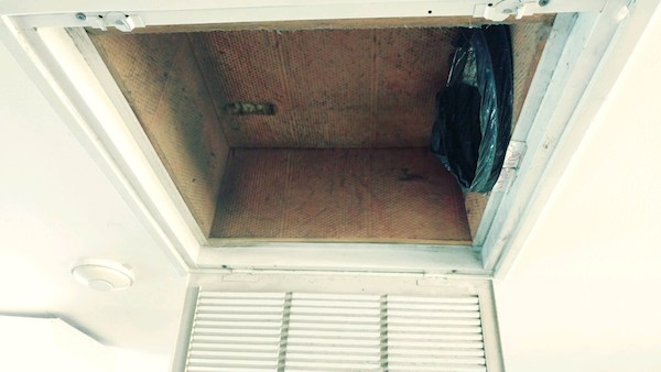 An open vent on a white ceiling with fiberglass walls and a flex duct off to one end.