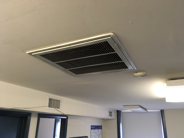 A white air vent on a ceiling of an office.