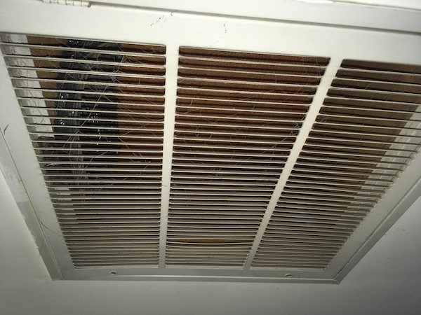 Close up of a white vent on a ceiling inside of an office.