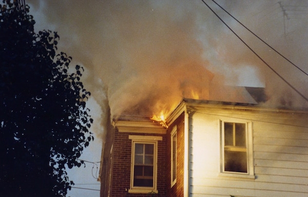 Flames coming out of the roof of a house.