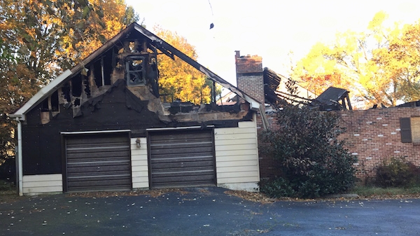 A house with the roof burned off view from the front of the double car garage.