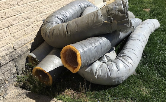 A pile of flex ducts laying outside which were removed from a building