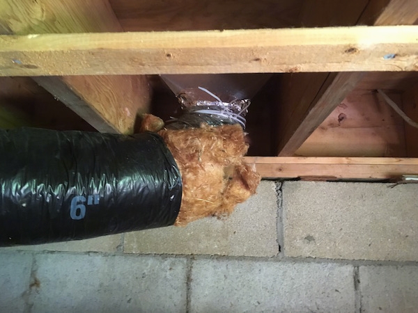 A flex duct connected to an air vent that leads to a dining room with a lot of exposed fiberglass all around the edges.