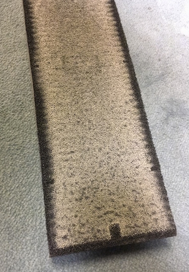 A dirty HEPA filter that pulled gray dust out of the air. The cartridge was once black and is now gray with black around the edges.