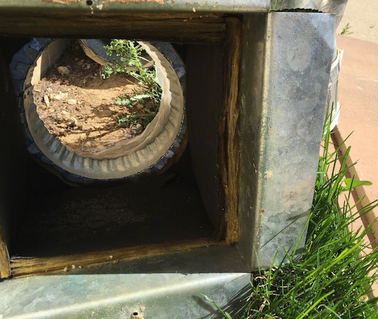 A section of a fiberglass lined duct laying outside after being removed