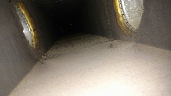 A view from the inside of a fiberglass lined duct with two air ducts shooting off to the left and right