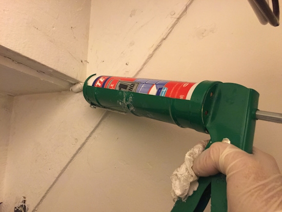 A green caulk gun filling a hole in the wall