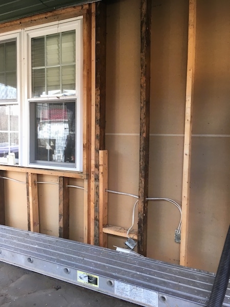 The clean wood walls of the outside of a house after the fiberlgass insulation was removed. There is a double window on the left.