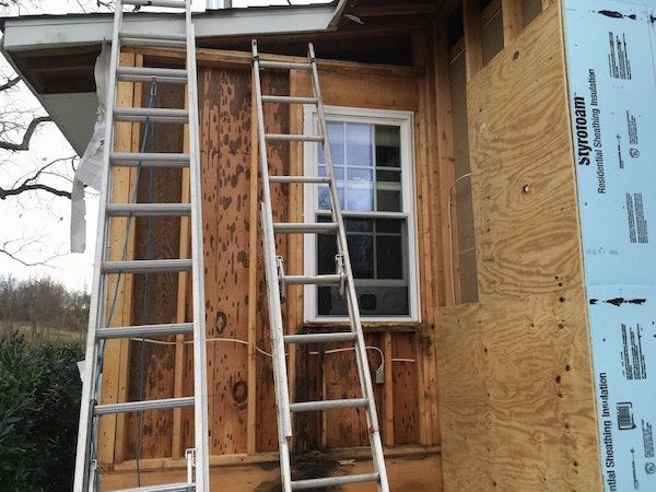 A house with the siding and the fiberglass removed showing a clean wall cavity and blue styrafoam on the right.