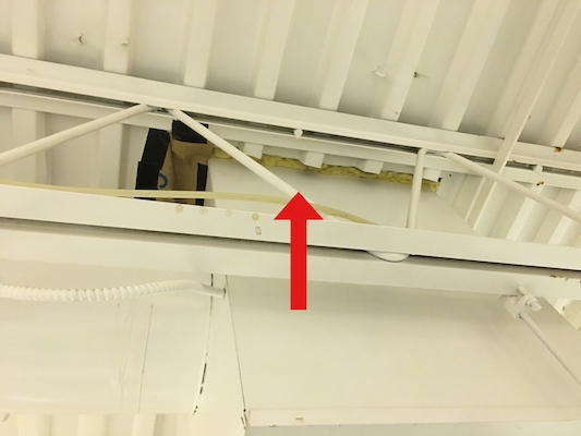 An arrow pointing to fiberglass insulation around the edges of an HVAC system