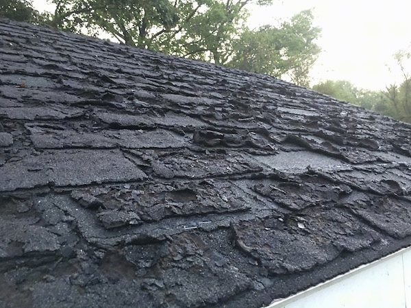 A very warn out black asphalt roof that is cracking and curling.