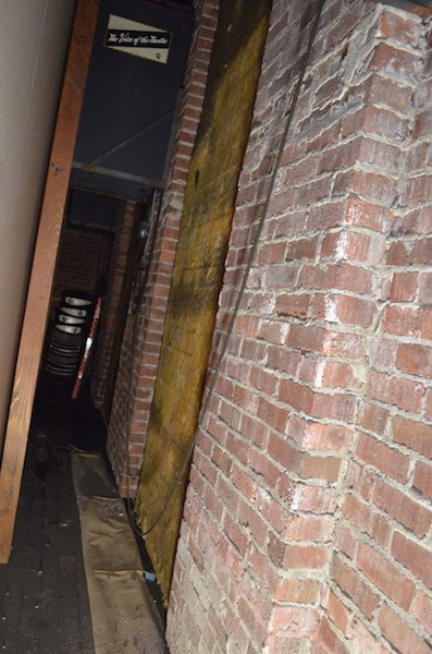 A brick wall with exposed fiberglass insulation tacked on it