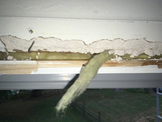 Yellow fiberglass in the crack around a window frame hanging out.