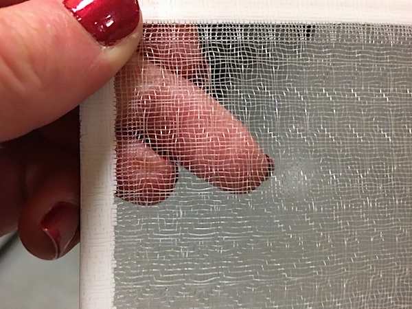 Close-up - A person with red painted fingernails holding a  white screen-like filter.