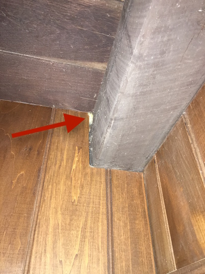 Fiberglass insulation shoved in a crack between a beam  and the wall on the ceiling of a home