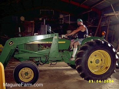 Bob inside a barn on a green John Deere Tractor