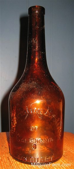 An old Bottle on a wooden table with a blue wall behind it.