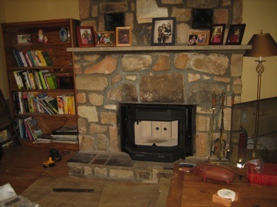 A black wood burning stove has been placed in the fireplace opening.