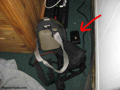 A red arrow pointing to a camera bag and its contents spilled all over the floor behind a This End Up wooden desk.